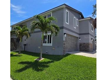 Charming exterior elevation features a gray stucco and stone exterior, attached garage, and manicured lawn at 1600 Pennsylvania Ne Ave, St Petersburg, FL 33703