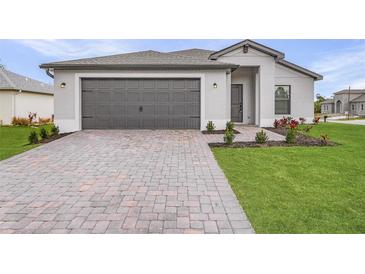 Attractive single-story home with a two-car garage, brick paver driveway, and well manicured landscaping at 5710 Humkey St, North Port, FL 34291