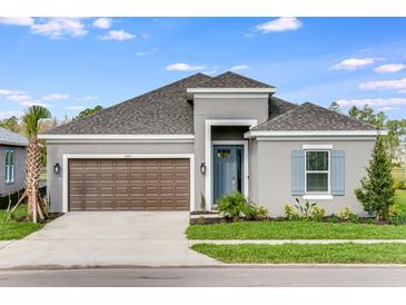 Charming home features a two-car garage, gray exterior, simple landscaping, and a pop of color on the front door at 2061 Longliner Loop, Wesley Chapel, FL 33543