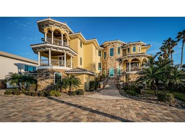 Stunning multi-story home featuring stone accents, balconies and lush landscaping at 335 Bath Club S Blvd, North Redington Beach, FL 33708