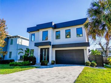 Modern two-story home featuring a black two-car garage, neutral colors, and meticulously manicured landscaping at 818 W Adalee St, Tampa, FL 33603