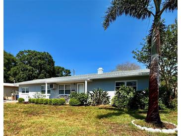 Charming single-story home featuring a well-manicured front yard with lush landscaping and a clear blue sky backdrop at 6623 16Th N St, St Petersburg, FL 33704