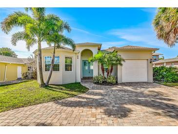 Charming single Gathering home with a paved driveway, lush lawn and tropical landscaping at 2026 20Th Avenue Pkwy, Indian Rocks Beach, FL 33785