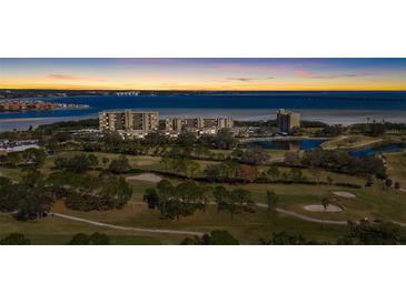 Beautiful aerial view of waterfront condos, lush golf course, and stunning bay at sunset at 2617 Cove Cay Dr # 604, Clearwater, FL 33760