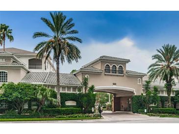 Exterior view of building 501 featuring an entrance portico, lush greenery, and a neatly landscaped entrance at 501 Knights Run Ave # 2119, Tampa, FL 33602