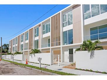 Modern townhome exterior features large windows, light wood accents, and a white privacy fence at 2702 N Woodrow Ave # 2, Tampa, FL 33602