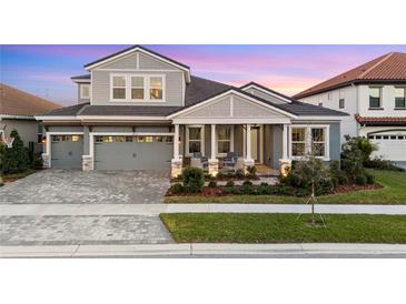 Charming two-story home with a well-manicured lawn, a brick driveway, and a covered front porch with chairs at 14215 Swiss Bridge Dr, Riverview, FL 33579