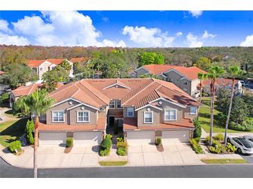 An eye-level aerial view of a two-story townhome featuring an attached garage, manicured landscaping and terracotta tile roof at 4984 Anniston Cir, Tampa, FL 33647