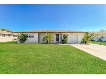 Charming single-story home with lush green lawn and mature landscaping under a clear blue sky at 10118 Hickory Hill, Port Richey, FL 34668