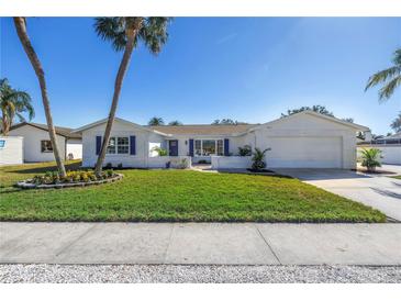 Charming single Gathering home featuring a lush front lawn, a beautiful garden, palm trees and two-car garage at 8418 Flagstone Dr, Tampa, FL 33615