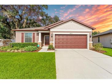 Charming single-story home featuring a well-manicured lawn, brown shutters, and an attached two-car garage at 15571 Stone House Dr, Brooksville, FL 34604