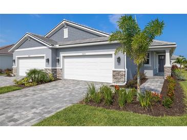 Charming home showcasing a three-car garage, well-manicured lawn, and a welcoming paved walkway leading to the front door at 18491 Green Garden Ct, Venice, FL 34293