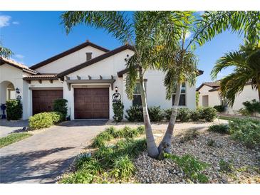 Beautiful home with a paver driveway, two car garage, and lush tropical landscaping at 17014 Clear Cork Dr, Wimauma, FL 33598