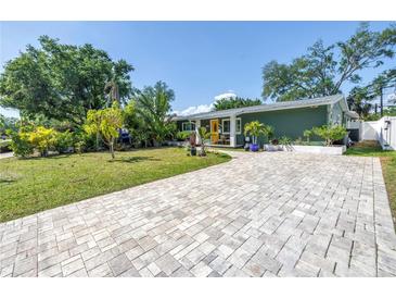Charming home featuring lush landscaping, a brick driveway, and a welcoming yellow door at 263 42Nd Ne Ave, St Petersburg, FL 33703