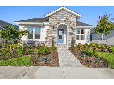 Beautiful one-story home featuring stone accents, manicured landscaping, and a welcoming blue front door at 687 Allora Ave, Nokomis, FL 34275