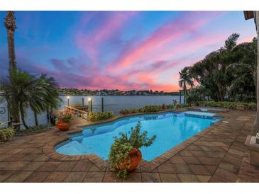 Inviting waterfront pool with brick surround and beautiful sunset views over the water at 1097 Eden Isle Ne Dr, St Petersburg, FL 33704
