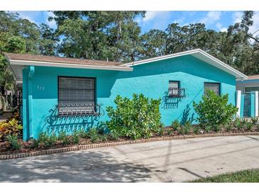 Charming home featuring a vibrant turquoise exterior, well-maintained landscaping, and newly paved driveway at 717 Carolina Ave, Tarpon Springs, FL 34689