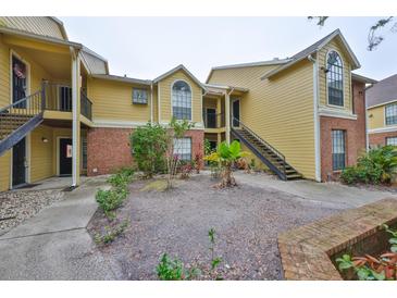 Yellow condo building featuring brick accents and landscaped courtyard at 8609 Mallard Reserve Dr # 103, Tampa, FL 33614