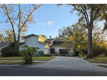 Charming home with a red front door, mature trees, long driveway and a well-manicured front lawn at 1735 Tall Pine Cir, Safety Harbor, FL 34695