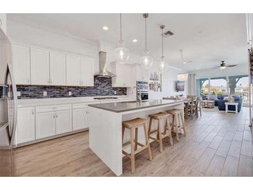 Bright kitchen boasts white cabinets, stainless appliances, and a large island with seating at 11721 1St E St, Treasure Island, FL 33706
