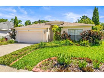 Charming single-story home featuring a well-manicured lawn and lush, colorful landscaping enhancing curb appeal at 4251 Whittner Dr, Land O Lakes, FL 34639