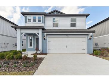 Charming two-story home featuring a two-car garage and manicured landscaping at 1165 Kistna Dr, Zephyrhills, FL 33540
