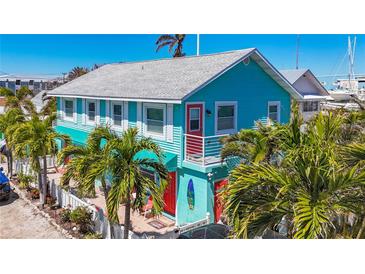 Charming turquoise two-story home with red door, white trim, and lush tropical landscaping near the marina at 308 2Nd St N # 202, Bradenton Beach, FL 34217