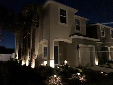 Elegant two-story home featuring manicured landscaping and exterior lighting at nighttime at 7055 Summer Holly Pl, Riverview, FL 33578