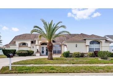 Stunning home featuring a well-manicured lawn, mature palm tree, and a grand entrance with an arched doorway at 9229 Water Hazard Dr, Hudson, FL 34667