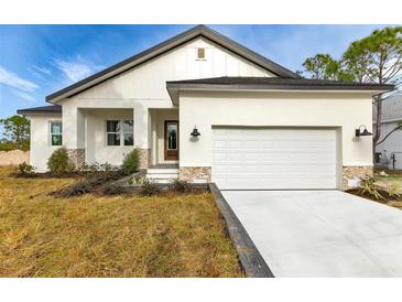 Charming single-Gathering home featuring a well-manicured lawn, two-car garage, and stone accents at 2436 Jacobs St, Port Charlotte, FL 33953