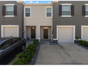 Modern townhome featuring an attached garage, gray stucco exterior and manicured landscaping at 8617 Falling Blue Pl, Riverview, FL 33578