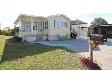 Charming manufactured home featuring colorful Adirondack chairs and lush lawn at 114 W Saint Johns Way, Apollo Beach, FL 33572