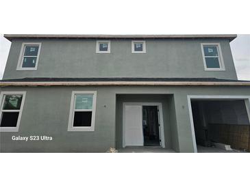 View of exterior elevation featuring a two-story home with gray facade, multiple windows, and attached garage at 3801 Luma Dr, Holiday, FL 34691