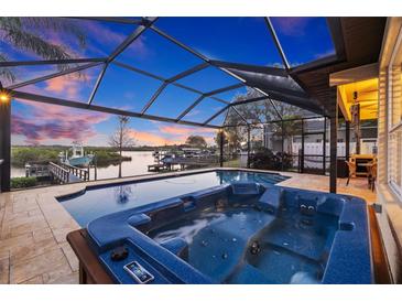 Screened-in pool with a hot tub overlooks a serene waterfront view, offering a luxurious outdoor retreat at 1881 Riveredge Dr, Tarpon Springs, FL 34689
