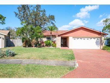 Charming single-story home with a brick driveway, lush landscaping, and a well-maintained lawn at 7425 118Th Dr, Largo, FL 33773