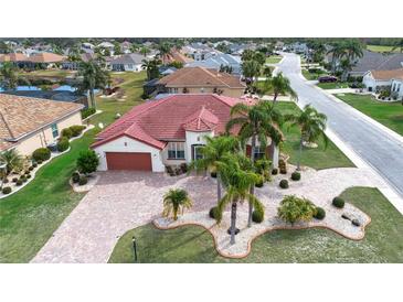 Stunning aerial view of a home with a red tile roof, palm trees, and a brick driveway at 1115 Signature Dr, Sun City Center, FL 33573