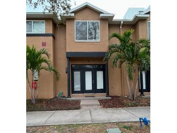 Charming townhome featuring a stucco exterior, a pair of palm trees, and a welcoming black double-door entrance at 724 4Th S Ave # 8, St Petersburg, FL 33701