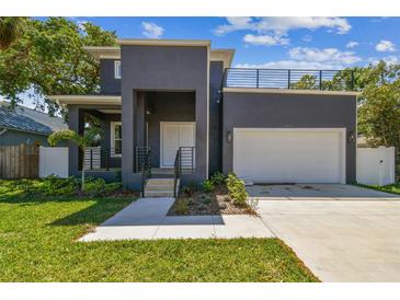 Contemporary two-story home with a gray exterior, a rooftop deck, and an attached one car garage at 4406 W Euclid Ave, Tampa, FL 33629