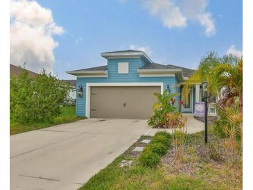 Charming single-Gathering home with a two-car garage, neat landscaping, and a light blue exterior at 11008 Sand Pine Ln, Parrish, FL 34219