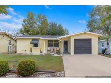 Charming single-story home with a well-maintained lawn, neutral paint, attached garage, and inviting front porch at 1230 7Th Ne Ave, Largo, FL 33770