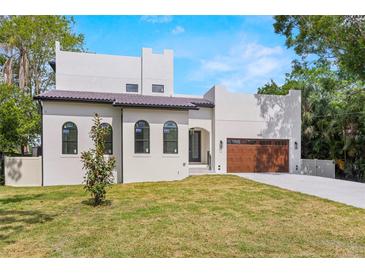 Charming two-story home with a tile roof, manicured lawn, and a driveway leading to a wooden garage door at 1802 E Park Cir, Tampa, FL 33610