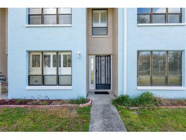 Charming light blue townhouse with a secure, decorative front door and a well-maintained walkway and landscaped garden at 1849 Abrico Dr # 4, Lutz, FL 33558