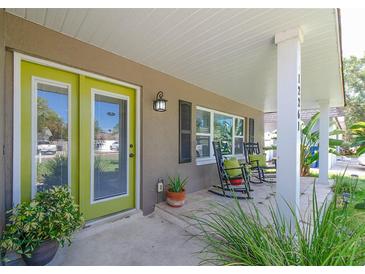 Inviting front porch with rocking chairs and a vibrant green door, complemented by lush greenery at 12261 Eldon Dr, Largo, FL 33774