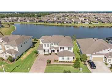 Expansive waterfront home features a brick driveway, manicured lawn, and stunning lake views at 7721 Roma Dune Dr, Wesley Chapel, FL 33545