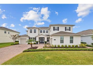 Elegant two-story home showcasing a lush front lawn, charming landscaping, and brick-paved driveway, under a bright sky at 7721 Roma Dune Dr, Wesley Chapel, FL 33545