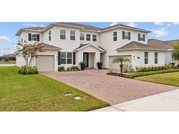 Charming two-story home boasts a brick driveway, three-car garage, and well-manicured lawn at 7721 Roma Dune Dr, Wesley Chapel, FL 33545