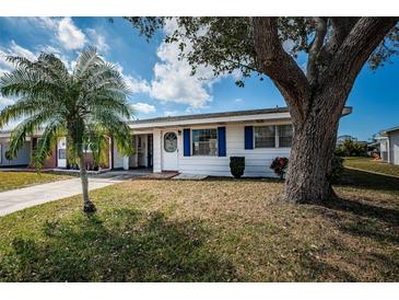 Charming single-story home boasts a well-maintained front yard with mature trees and vibrant blue shutters at 10022 Lily N St # N, Pinellas Park, FL 33782