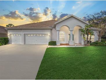 Charming single-story home features a well-manicured lawn, a three-car garage, and a welcoming arched entryway at 1545 Deerbourne Dr, Wesley Chapel, FL 33543