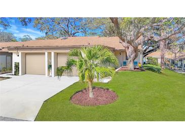 Charming home featuring a two-car garage, well-manicured lawn and mature trees offering a welcoming curb appeal at 2606 Oak Cir, Tarpon Springs, FL 34689