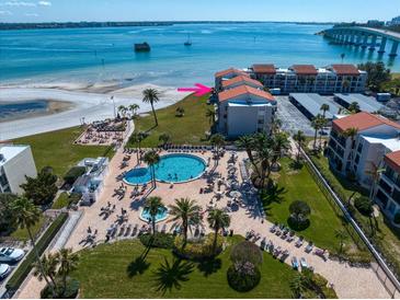 Aerial view of condo resort featuring a pool, palm trees, manicured landscaping, and nearby beach access at 825 S Gulfview Blvd # 208, Clearwater Beach, FL 33767